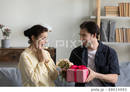 Happy excited mature mother getting present and flowers from son 88014993