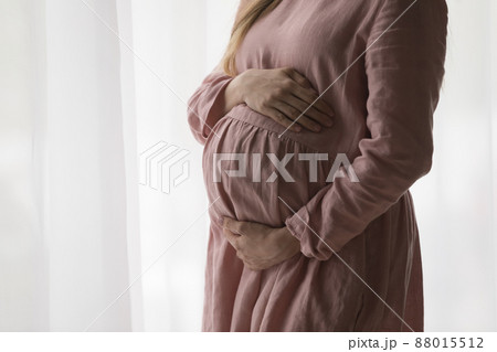 Expecting mom wearing natural dress for pregnant, holding big tummy Expecting mom wearing natural dress for pregnant, holding big tummy 88015512