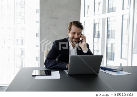 Happy concentrated young businessman multitasking in modern office. 88015832
