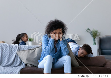 Frustrated young African mom tired of watching hyperactive children Frustrated young African mom tired of watching hyperactive children 88015834