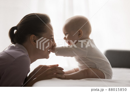 Joyful young mom playing with baby at home, enjoying motherhood Joyful young mom playing with baby at home, enjoying motherhood 88015850
