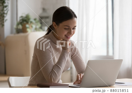 Young woman sit at table in domestic kitchen using laptop Young woman sit at table in domestic kitchen using laptop 88015851