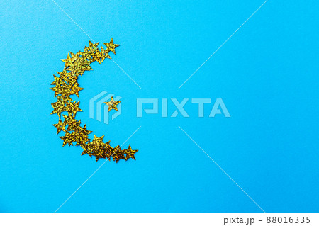Shape of moon from glowing glitters. Blue background, copy space and top view. 88016335