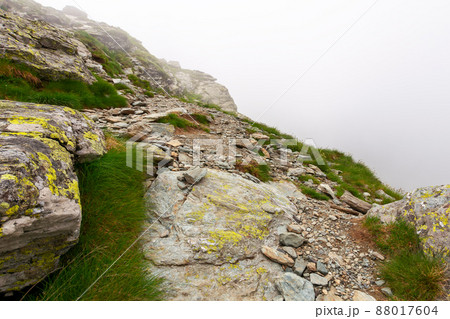 steep slopes of fagaras mountains in fog. huge rocks on grassy hills. travel romania in summer steep slopes of fagaras mountains in fog. huge rocks on grassy hills. travel romania in summer 88017604