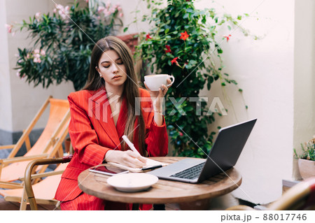 Thoughtful businesswoman drinking coffee and taking notes in journal in cafe Thoughtful businesswoman drinking coffee and taking notes in journal in cafe 88017746