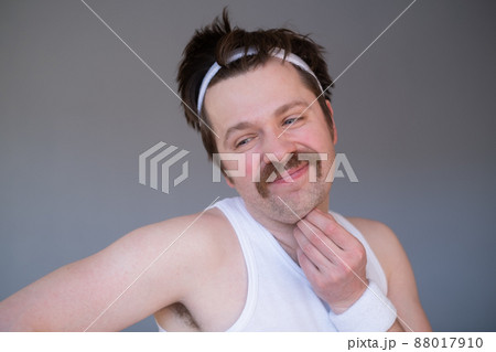 Athletic funny young man doing exercise dumbbell. Studio shot on yellow shot 88017910