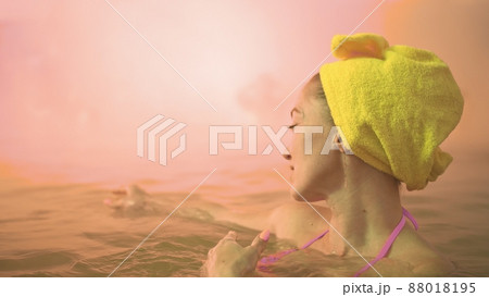 Close up caucasian woman in a swim in hot saline mineral water bath at a traditional spa outdoor with soft magic pink lighting steam. Geothermal spa. 88018195