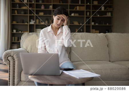 Anxious unhappy young Hispanic woman having financial problems. 88020086