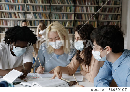 Happy millennial diverse students in facial masks preparing for exams. Happy millennial diverse students in facial masks preparing for exams. 88020107