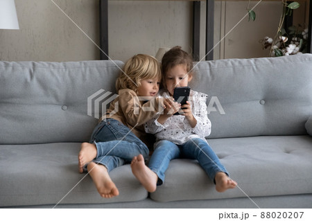 Happy little adorable kids playing games on cellphone. 88020207