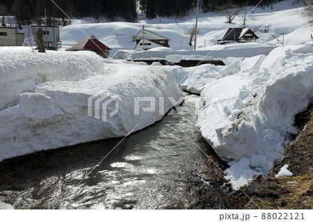 雪の壁を流れる布沢川と残雪に埋まる集落　福島県只見町 88022121