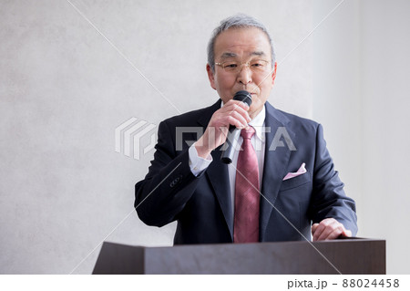 ビジネス　マイクを持ってスピーチをするシニア男性 88024458