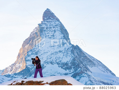 Woman photographer capturing mountain views of Swiss Alps with Matterhorn in background Woman photographer capturing mountain views of Swiss Alps with Matterhorn in background 88025963