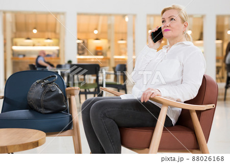 Mature woman sitting in a museum hall and talking on smartphone 88026168