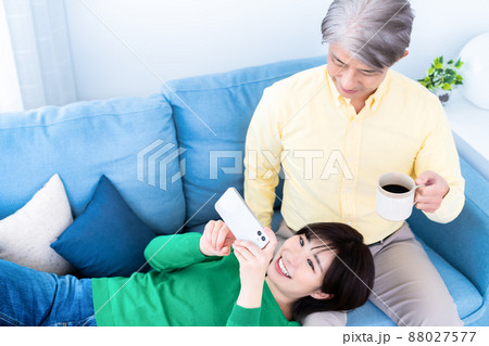 リビングのソファでくつろぐミドルの父と若い娘の親子 リビングのソファでくつろぐミドルの父と若い娘の親子 88027577