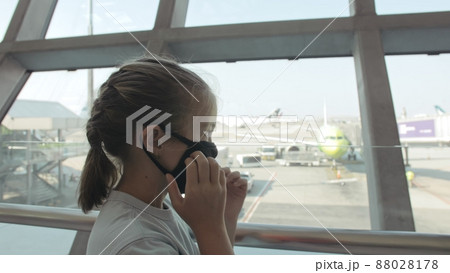 Children caucasian at airport with wearing protective medical mask on head against the background of plane. Coronavirus sars-cov-2 covid-19 2019-ncov. Children caucasian at airport with wearing protective medical mask on head against the background of plane. Coronavirus sars-cov-2 covid-19 2019-ncov. 88028178