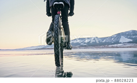 Man is riding bicycle on the ice. Ice of frozen Lake Baikal. Tee 88028223