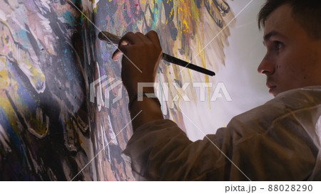 Artist designer draws an eagle on the wall. Craftsman decorator paints picture with acrylic oil color. Painter painter dressed in paint coat. Indoor. 88028290