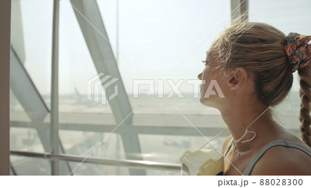Woman caucasian at airport with wearing protective medical mask on head against the background of the plane. Coronavirus sars-cov-2 covid-19. 88028300