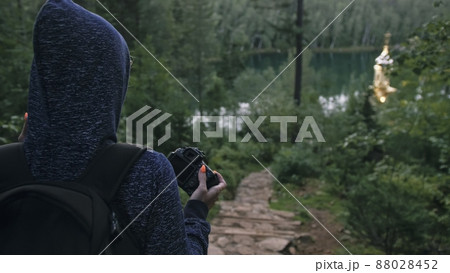 Traveler photographing scenic view in forest. One caucasian woman shooting nice magic look. Girl take photo video on dslr mirrorless camera. 88028452