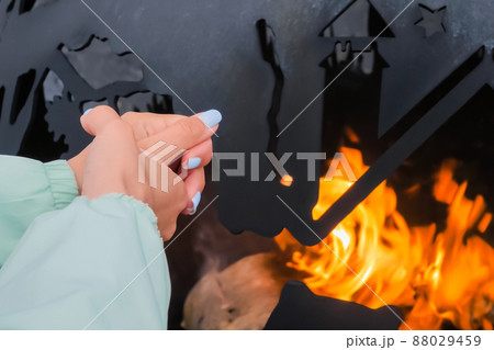Woman warms hands over flame outdoor - close up Woman warms hands over flame outdoor - close up 88029459