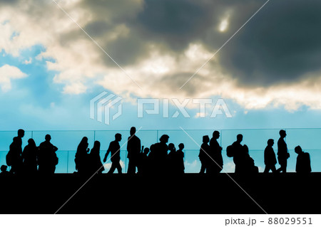 Unrecognizable people silhouettes walking on bridge against blue cloudy sky 88029551