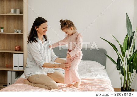 A young mother plays with her baby in the bedroom. Happy loving family. 88030407