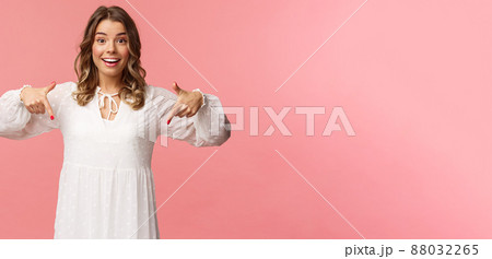 Portrait of enthusiastic upbeat young blond woman pointing fingers down to invite you check-out product, showing bottom advertisement, smiling camera cheerful, spring concept, pink background Portrait of enthusiastic upbeat young blond woman pointing fingers down to invite you check-out product, showing bottom advertisement, smiling camera cheerful, spring concept, pink background 88032265