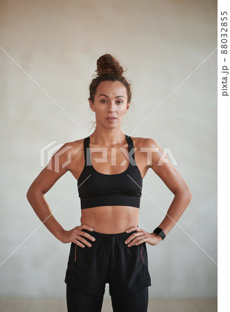 Vertical medium portrait of young adult Caucasian woman with muscular body wearing sports clothes looking at camera Vertical medium portrait of young adult Caucasian woman with muscular body wearing sports clothes looking at camera 88032855