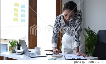 Female accountant standing and using calculator at office desk. 88033293
