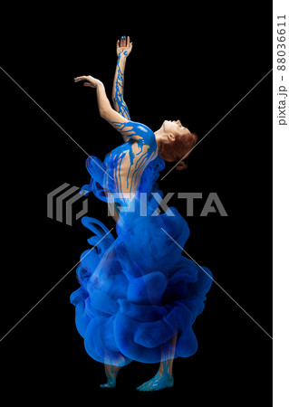Portrait of young beautiful woman covered with black thick pain and dye splash dancing isolated over black background. Emotive dance Portrait of young beautiful woman covered with black thick pain and dye splash dancing isolated over black background. Emotive dance 88036611