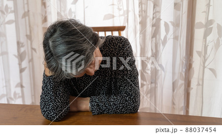 頭をもたげ考え込んでいる黒い服を着た高齢者女性 88037454