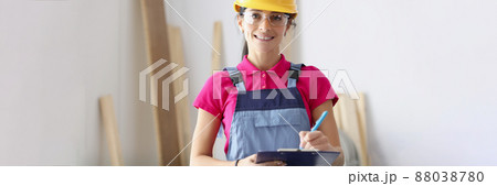 Woman builder in protective helmet holding clipboard with documents Woman builder in protective helmet holding clipboard with documents 88038780