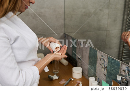 Close-up of a beautiful pregnant young woman taking pills with beauty and health supplements, having diet nutrition, standing in the home bathroom Close-up of a beautiful pregnant young woman taking pills with beauty and health supplements, having diet nutrition, standing in the home bathroom 88039039