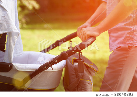 A young dad walking in the park with a baby in a stroller. Close-up of men's hands with a stroller. Father's Day concept. High quality photo 88040892