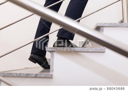 a businessman moves up the steps to the top, close-up of the steps and male legs a businessman moves up the steps to the top, close-up of the steps and male legs 88043686