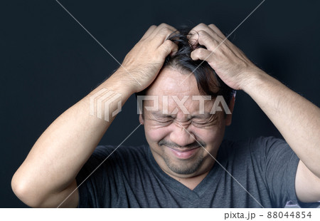 Middle age man has itching in his hair on black background, 88044854