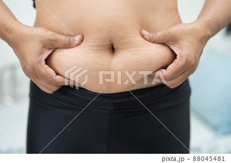 Overweight Asian woman show fat belly at office. 88045481