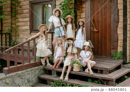 Tween girls posing together on doorstep of wooden country house in summer 88045801
