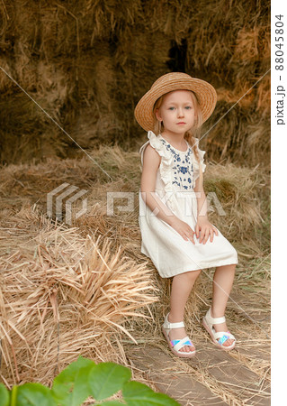 Dreamy blonde preteen girl resting on hayloft in summer 88045804