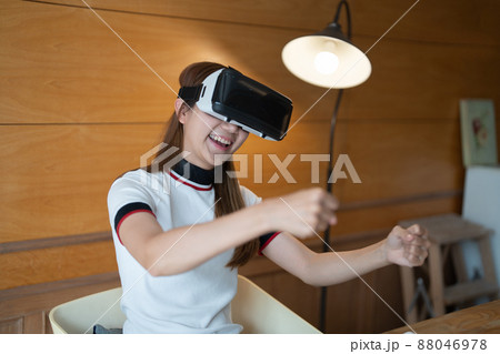 Excited young woman in VR goggles driving car in virtual reality. Lady screaming when turning virtual steering wheel, teen playing in racing computer game or road simulator. 88046978
