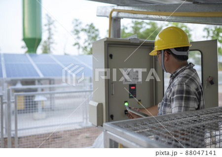 Technician at groundwater pumping station with solar or alternative energy uses a tablet to control and monitor. 88047141
