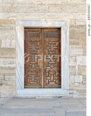 Wooden aged engraved door and exterior stone wall, Istanbul, Turkey 88048987