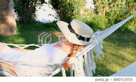 funny senior woman in a straw hat smiling happy relaxing on a hammock enjoying the fresh air on the 88051050
