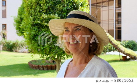 portrait of a mature woman 55-60 years old with a toothy smile in a sun-protective straw hat 88051052