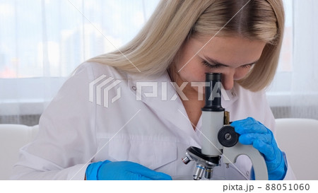 Young scientist laboratory assistant looks through a microscope in the laboratory. A young scientist 88051060