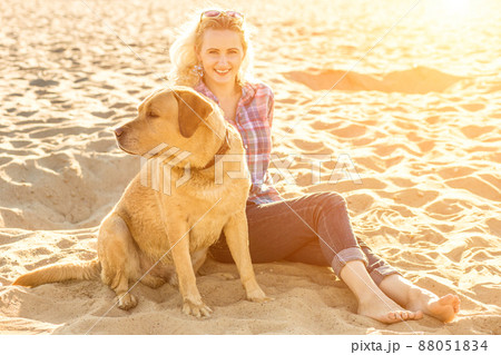 Young woman with her dog at the beach. Sun flare Young woman with her dog at the beach. Sun flare 88051834