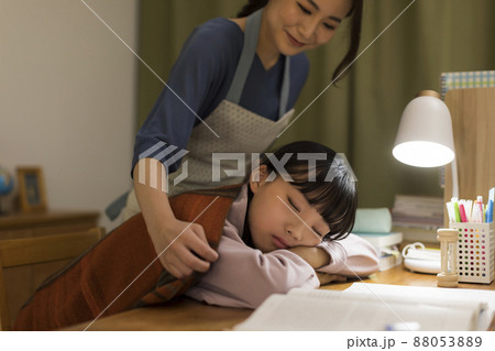 机で居眠りをする娘に毛布をかける母親 机で居眠りをする娘に毛布をかける母親 88053889
