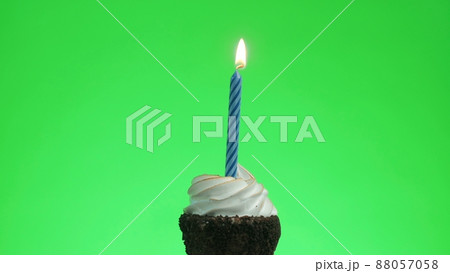 I light a blue candle on a delicious cupcake. Green screen 88057058