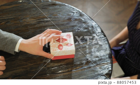 A man takes a gift box from under the table and puts it on the table in a cafe or restaurant close up A man takes a gift box from under the table and puts it on the table in a cafe or restaurant close up 88057453